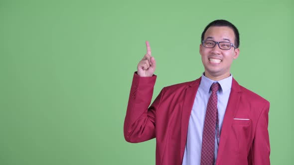 Happy Asian Businessman with Eyeglasses Pointing Up