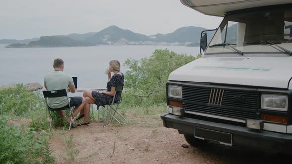 Young  travel couple sitting near motor home RV campervan.