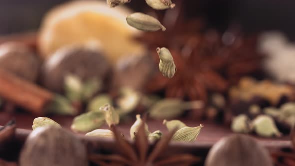 Cardamom Falling Among Spices on Wood
