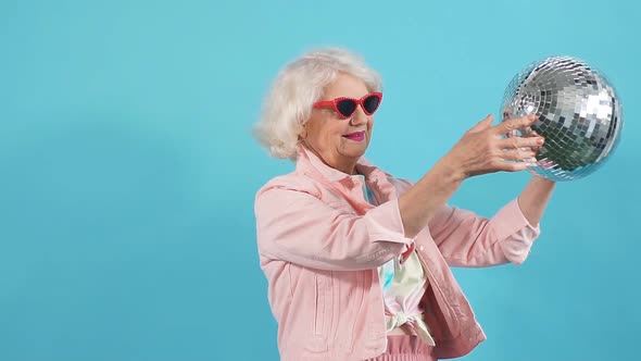 Funny Old Woman in Sunglasses Holding a Disco Ball