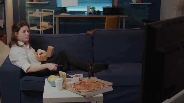 Young Woman Laying on Couch While Eating Burger