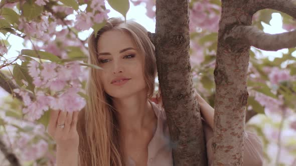 Spring Beauty Portrait of a Woman at Blossoming Sakura Tree on Nature