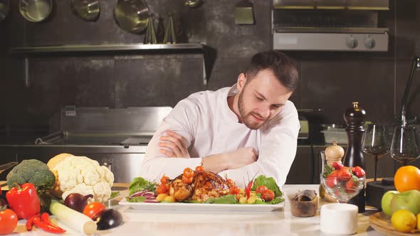 Young Male Chef Presents His Special Dish. He Stands in a Big Restaurant Kitchen