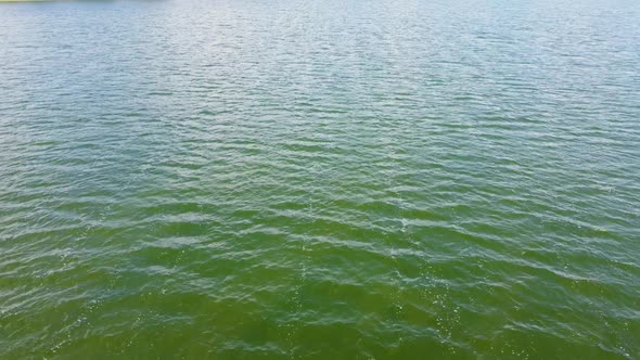 Closeup of a Drone Shot Over Green Smooth Water Surface