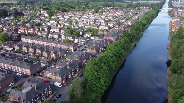 Aerial view flying above wealthy Cheshire housing estate alongside Manchester ship canal panning lef