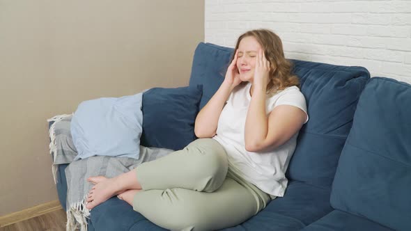 Young Woman is Sitting on the Bed She Has Migraine