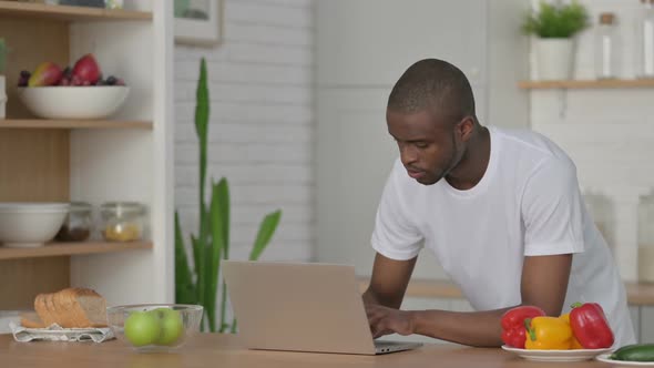 Sporty African Man Working on Laptop in Kitchen
