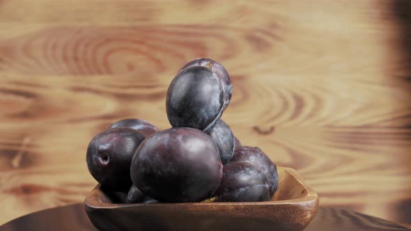 Plum on a Wooden Rotating Cup on a Wooden Background