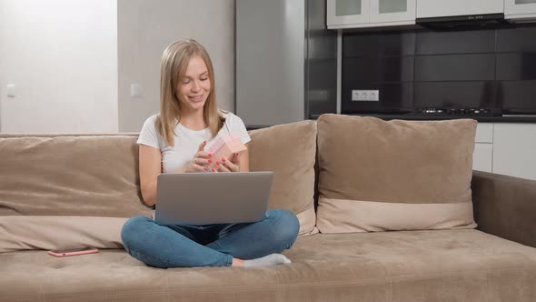 Positive Lady Opening Gift Box During Video Call on Laptop