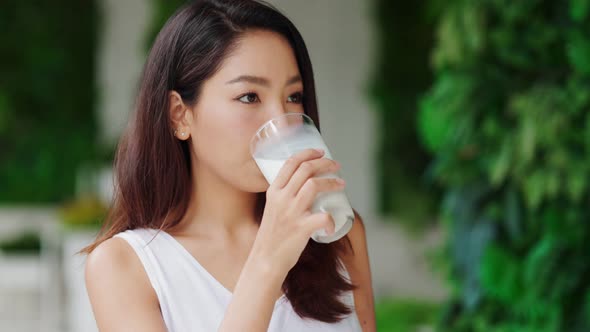 Attractive Asian woman drinking milk and smiling at home close up face.healthy life