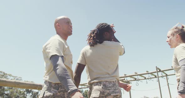 Happy diverse fit group of soldiers high fiving in field, at army obstacle course in the sun