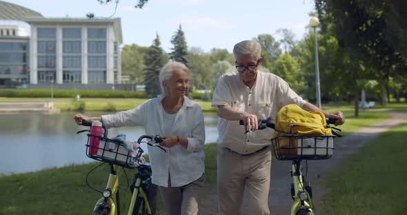 Senior Husband and Wife with Bicycle Walk Outdoors in Park