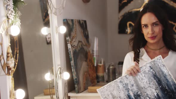 Young Woman Holding a Painting Made of Epoxy Resin and Looks in the Camera