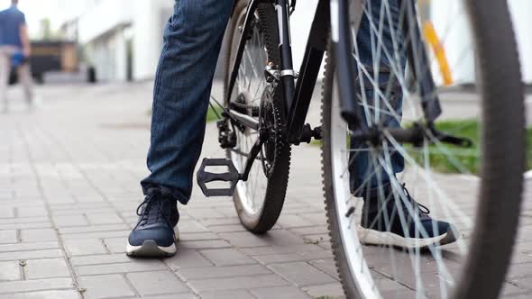 Closeup of Unrecognizable Cyclist Placing Foot on Bike Pedal and Starts Riding on City Street