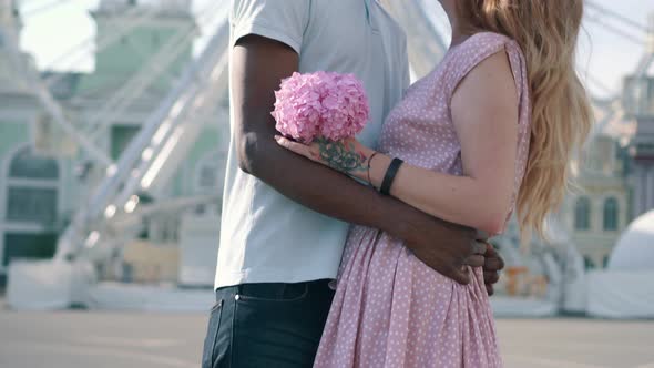 Young Interracial Couple Hugging Near Ferris Wheel in the City
