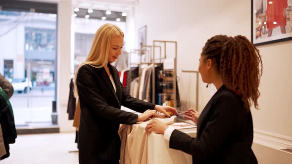 Positive multinational saleswomen examines clothes