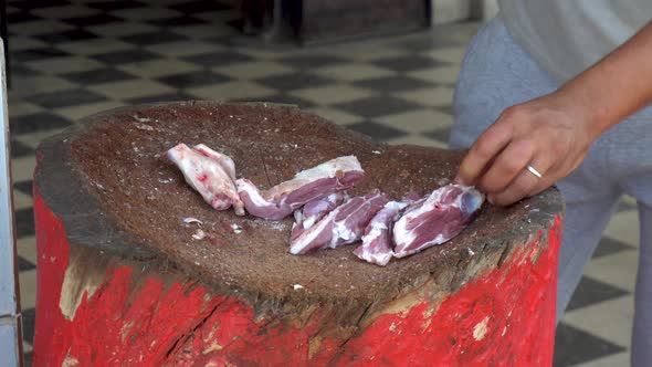 A Man Is Chopping with a Cleaver Fresh Meat of a Ram. Man Cuts Bones for Frying