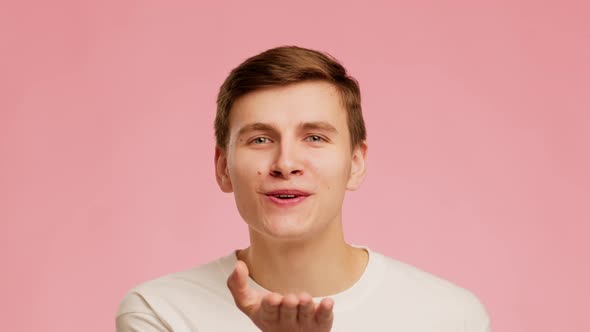 Playful Guy Blowing A Kiss Smiling Posing Over Pink Background