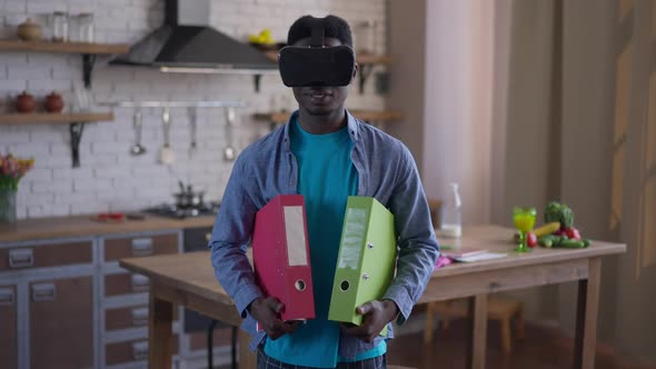 Middle Shot of Young Confident African American Man in VR Headset Holding Document Folders Turning