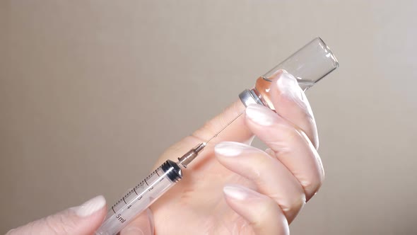 Nurse Filling Syringe Out of Vaccine Bottle with Transparent Liquid