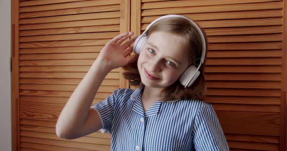 Modern Teenage Girl Dancing and Smile at Home with White Wireless Headphones