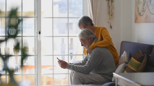 Couple of two old and mature people at home using tablet together in sofa. Senior use laptop