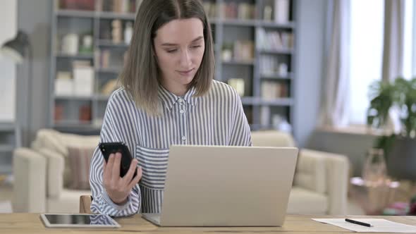 Attractive Young Woman Using Smartphone in Loft Office