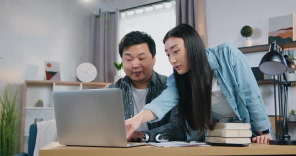 Asian Couple Working Together Over Joint Business Project and Discussing Different Details 