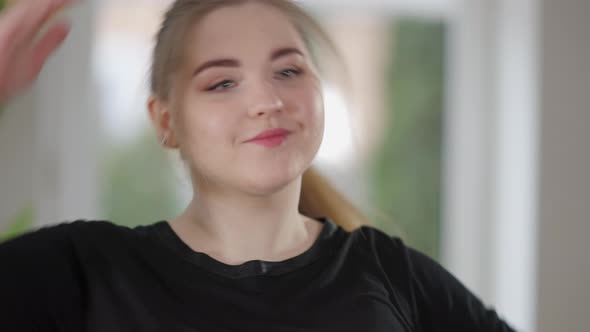 Closeup Portrait of Charming Plump Caucasian Sportswoman Warming Up Neck Muscles on Morning Training