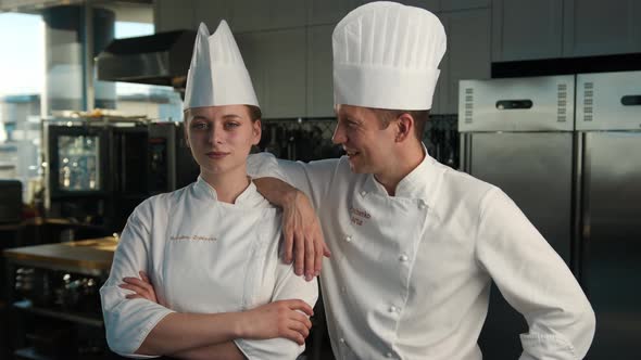 Professional kitchen, portrait: Female and Male Chef stand side by side in the kitchen