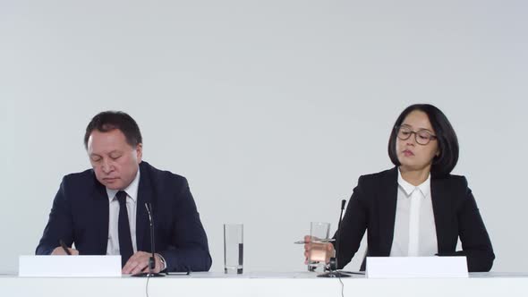 Two Asian People Making Notes during Conference Meeting