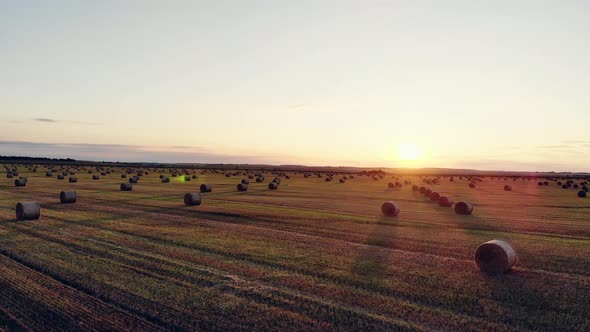 Field with Straw Bales Under Sunset Sky  Drone Aerilal Shot