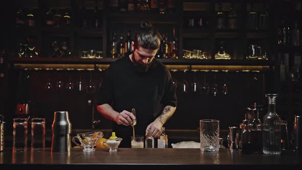Professional Bartender Stirs Cocktail in Glass with Spatula