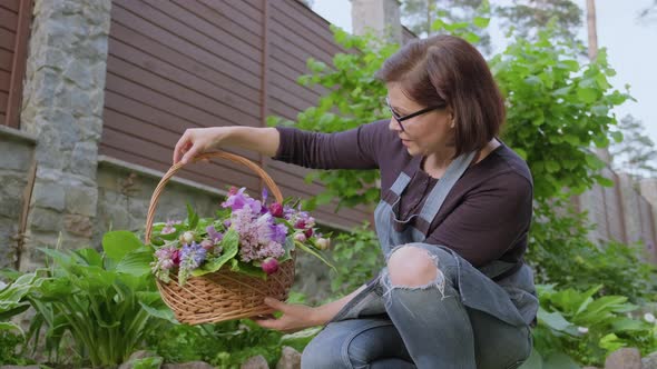 Woman Gardener Florist in Garden with Basket of Fresh Plucked Garden Spring Flowers