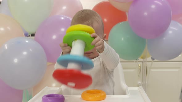 Happy Baby Boy Playing with Pyramid Toy Against Colorful Balloons Cute One Year Old Kid Stacking