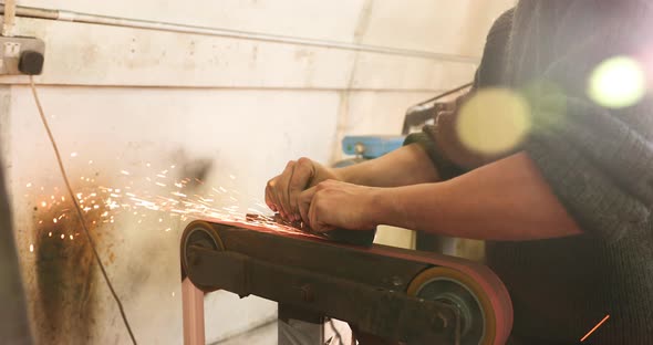 Bladesmith deburring a blade on belt grinder