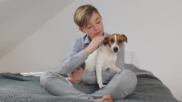 Young boy cuddling his dog at home