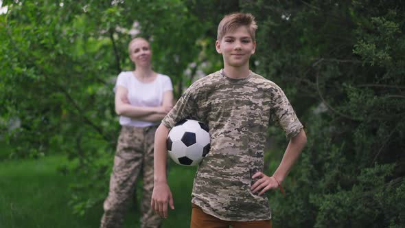 Medium Shot Confident Teenage Boy with Soccer Ball Gesturing Thumb Up Looking at Camera Smiling As