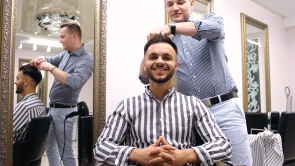 An Experienced Hairdresser Is Just Finishing His Work. The Customer Is Very Satisfied with the