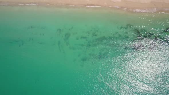 Aerial view of emerald green waters tracking to sandy beach with trees in Thailand