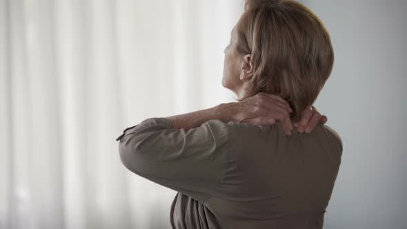 Elderly Woman Standing Backwards, Rubbing Neck and Shoulders, Stiff Muscles