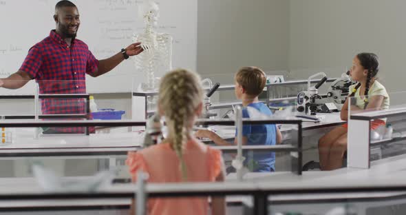 Video of happy african american teacher with class of diverse pupils during anatomy lesson