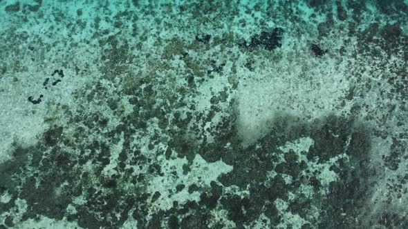 Rising aerial over private yachts parked at luxury island. Top view of seafloor visible from shallow