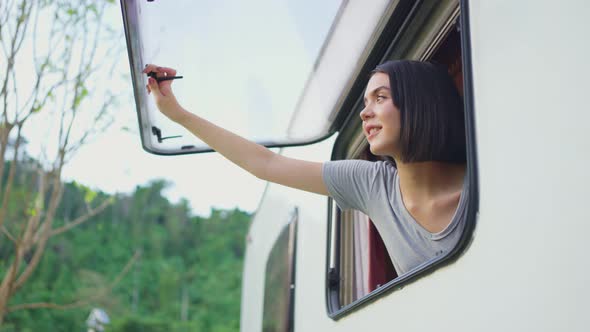 Asian young girl traveler feeling relax on camper van open window in the morning with happiness.