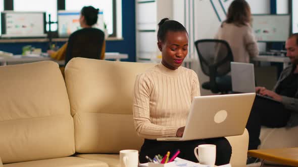 Portrait of African Woman Typing on Laptop Looking at Camera Smiling