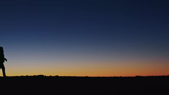 Cinematic View of Traveler Silhouette Walking By High Mountain at Golden Sunset