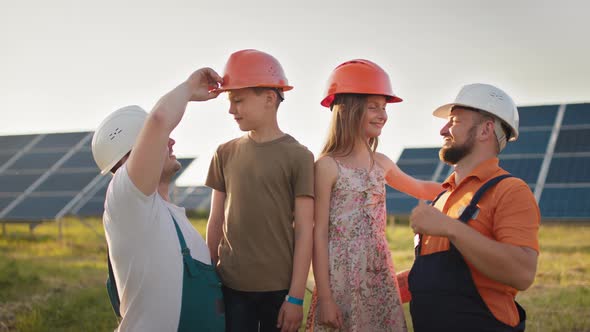 Portrait of Two Dads and Two Kids in Protective Helmets at a Solar Power Plant