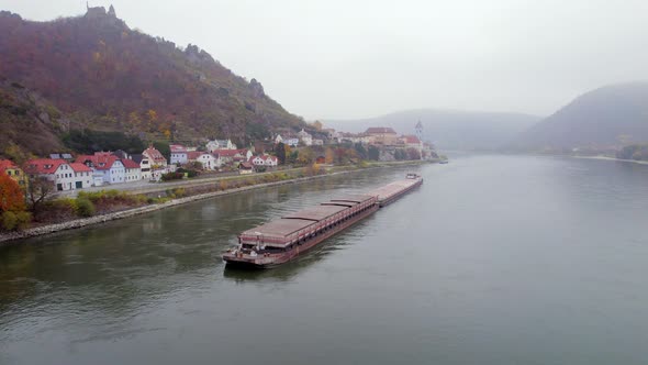 Cargo Pusher Boat on a River Transporting Cargo and Goods Past a Town