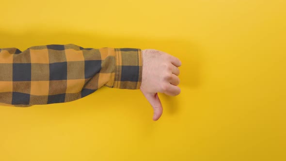 A man's hand appears on the left side of the screen and gives a thumbs down. Yellow background.