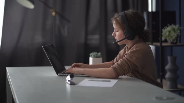 Teen Girl School Student Wearing Headphones Watching Internet Video Course Sitting at Home Desk